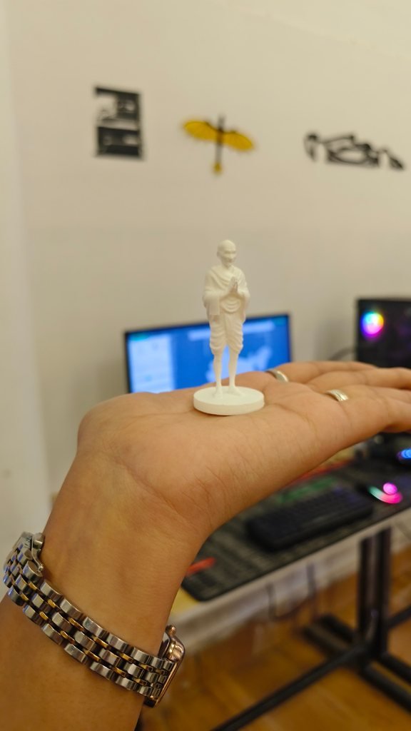 A small white 3D printed figure of Mahatma Gandhi held on a palm