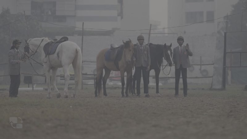 Students with horses at the riding ground on a misty morning