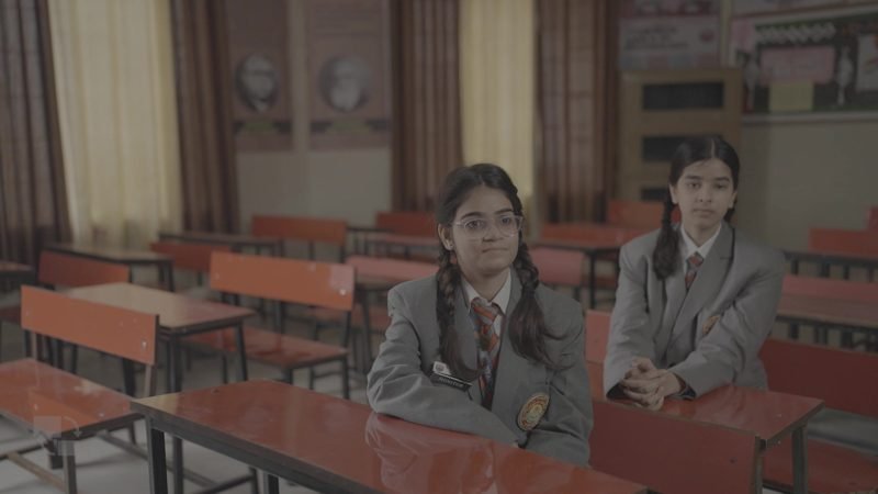 Two students seated at desks in a classroom