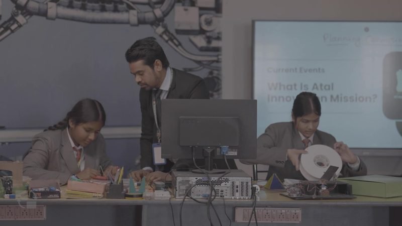 Teacher guiding students at the robotics and electronics bench