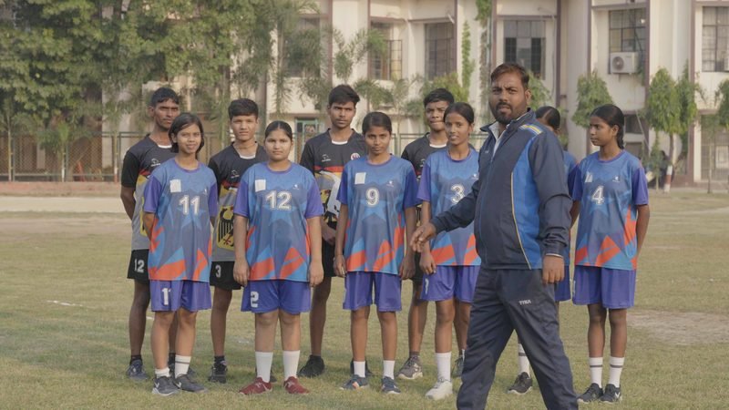 The school football team with their coach on the playing field, Rohania