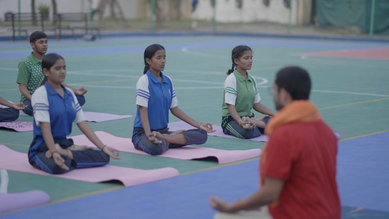 Students in a yoga session on the sports court, Rohania
