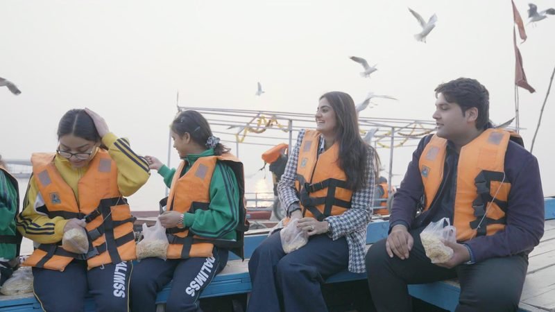 Students in life jackets on a boat ride on the Ganga, with gulls overhead