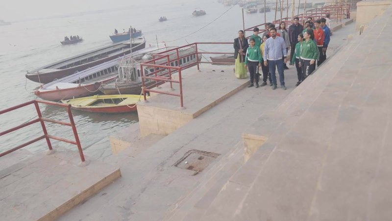 Students and teachers walking along the ghat steps beside the river boats