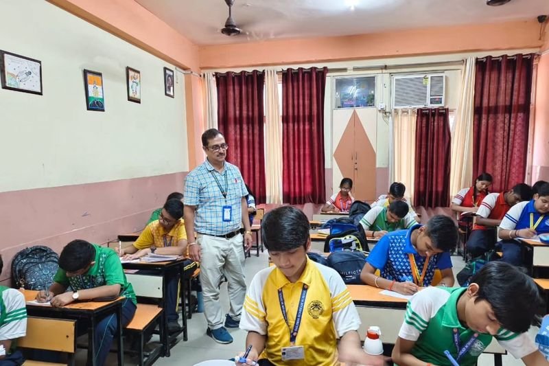 Students writing in a classroom with their teacher at Dalimss Sunbeam Global School, Ramkatora